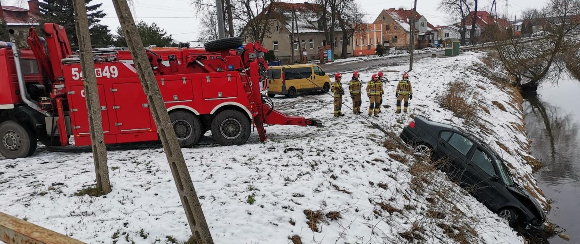 Pojazd ratowniczy wyciąga samochód osobowy z koryta rzeki