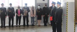 Zdjęcie przedstawia Komendanta Powiatowego PSP w Lesku, st. bryg. Dydek Jacek, odchodzącego na zaopatrzenie emerytalne, st. ogn. Jerzego Biodrowicza. W tle stoją funkcjonariusze i pracowników cywilni Komendy Powiatowej PSP w Lesku trzymający okolicznościowe prezenty.