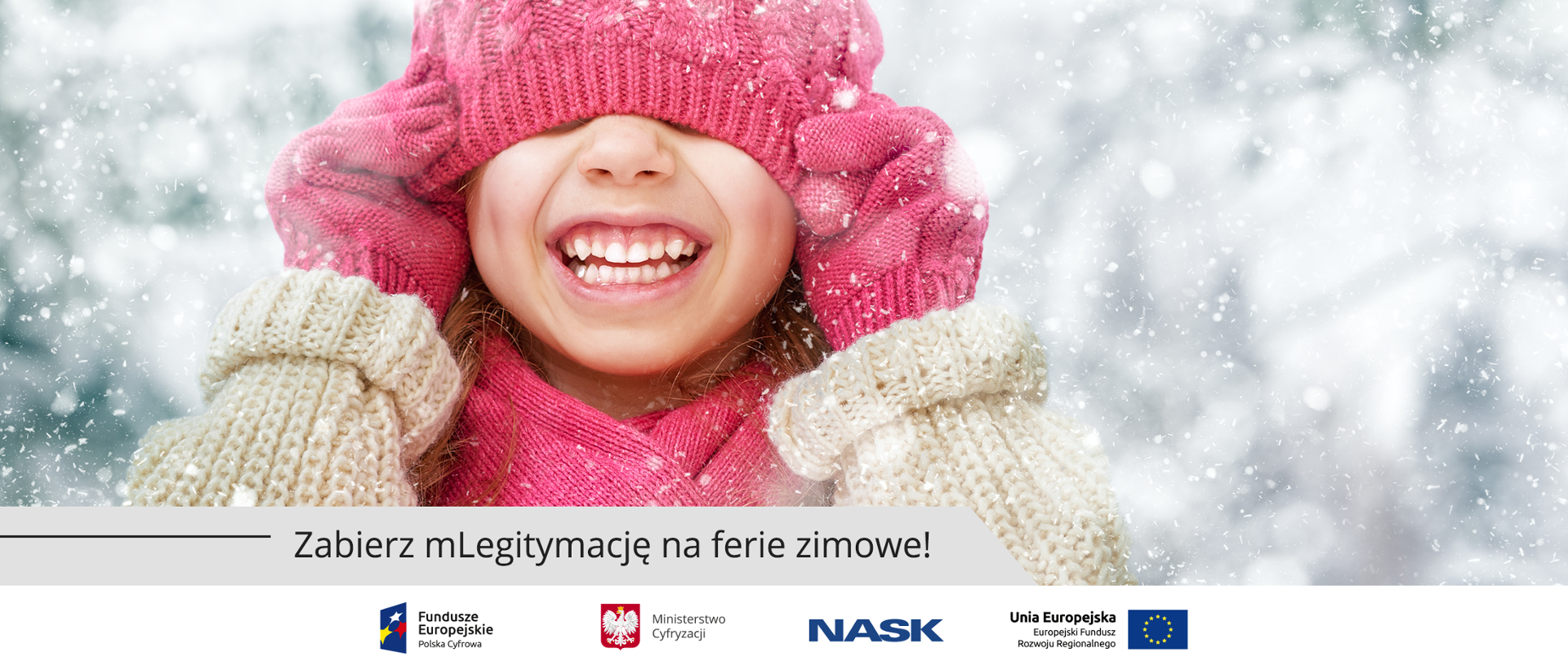 Uśmiechnięta dziewczyna w zimowej aurze naciąga dla żartu czapkę na oczy.