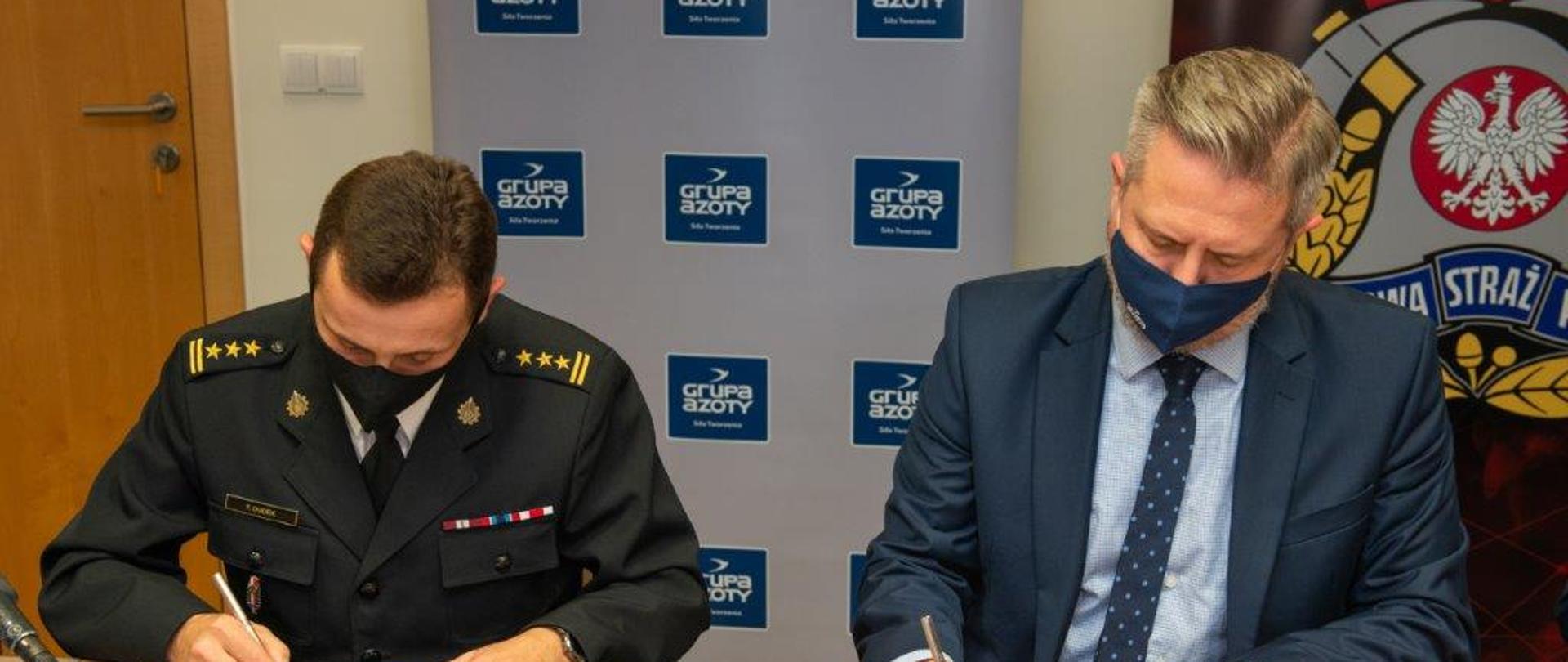 Mężczyźni siedzą przy stole i podpisują dokumenty