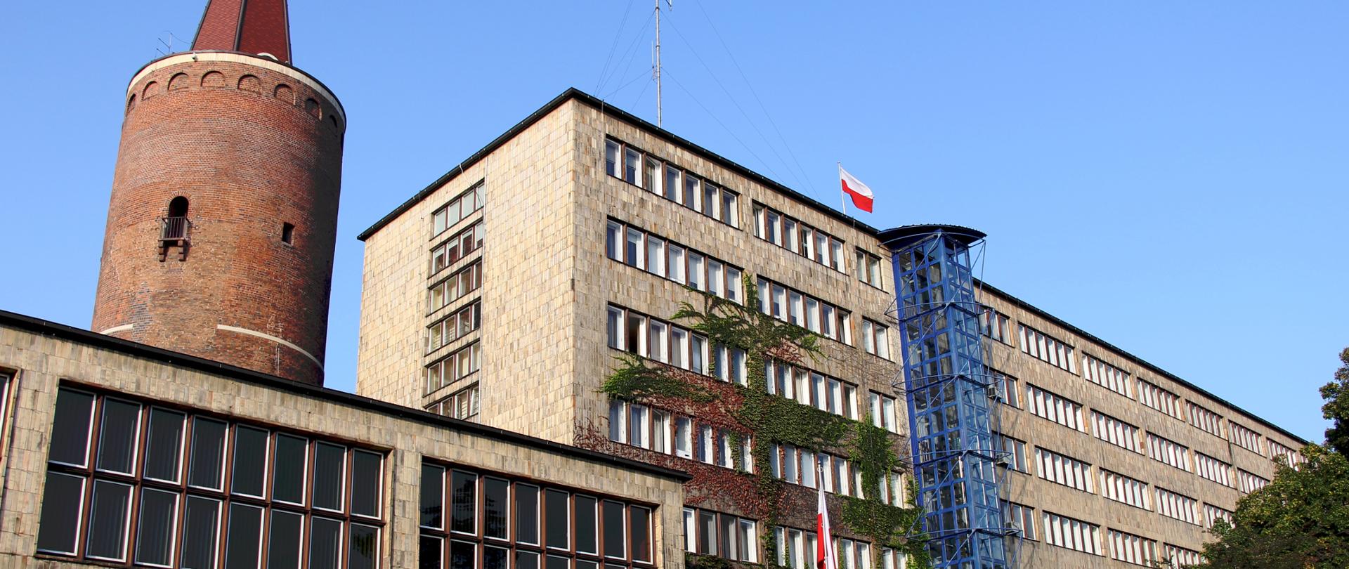 Budynek Opolskiego Urzędu Wojewódzkiego, wejście główne od strony ulicy Piastowskiej. Za budynkiem Wieża Piastowska.