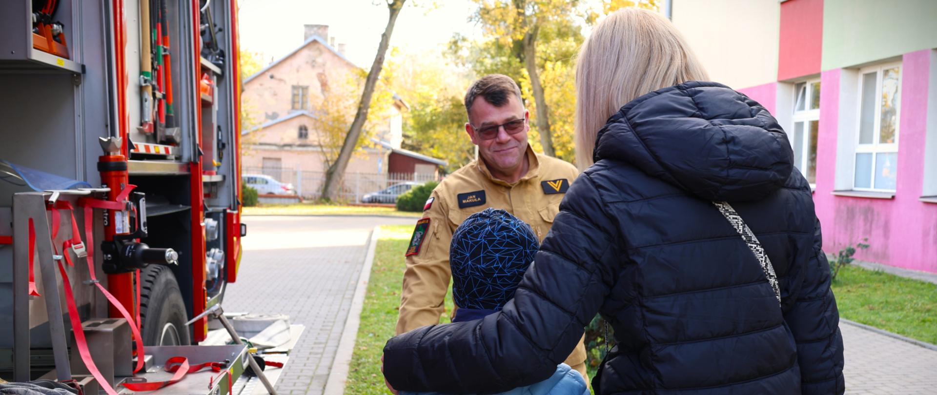 17 października Krajowy Trening Rodzinny - strażak objaśnia zebranym kwestie dotyczące alarmowania i pokazuje wóz strażacki i jego wyposażenie