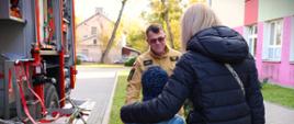 17 października Krajowy Trening Rodzinny - strażak objaśnia zebranym kwestie dotyczące alarmowania i pokazuje wóz strażacki i jego wyposażenie