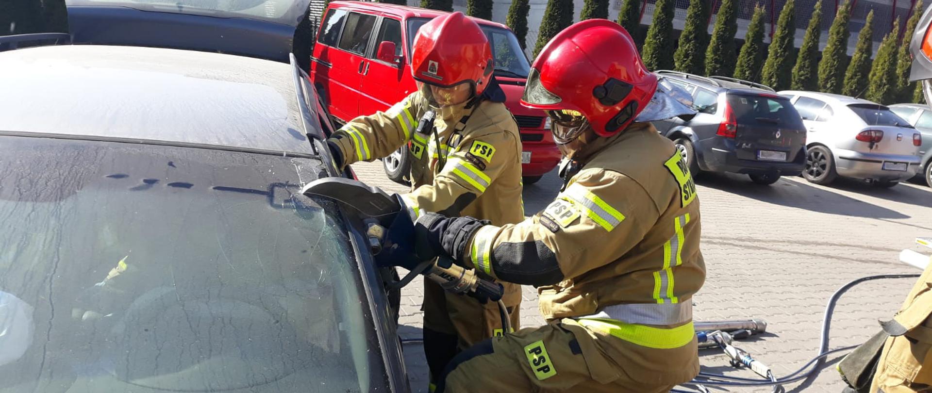 Strażacy przy użyciu narzędzi hydraulicznych wykonują dostęp do manekina przez przecięcie słupków przy lewych przednich drzwiach samochodu. 