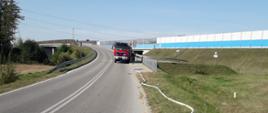 Średni samochód gaśniczy OSP z powiatu brzezińskiego, rozwinięta linia gaśnicza podczas ćwiczeń na drodze powiatowej między m. Kałęczew i Dmosin gm. Dmosin