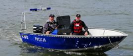 Zdjęcie przedstawia policjanta i strażaka w łodzi policyjnej podczas patrolu na jeziorze Raduń