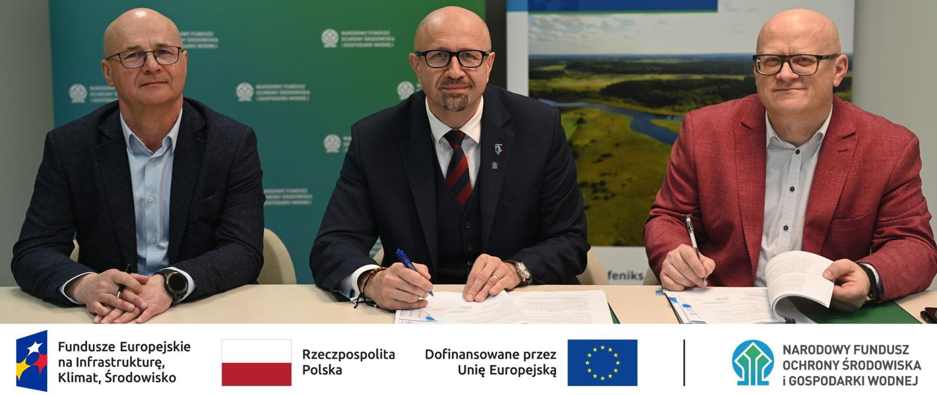 Zdjęcie grupowe. W stopce grafiki ciąg logotypów: Fundusze Europejskie na Infrastrukturę, Klimat, Środowisko, flaga Rzeczypospolita Polska, flaga UE i Dofinansowane przez UE, NFOŚiGW.
