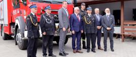 zaproszeni goście robią sobie pamiątkowe zdjęcie na tle samochodu strażackiego