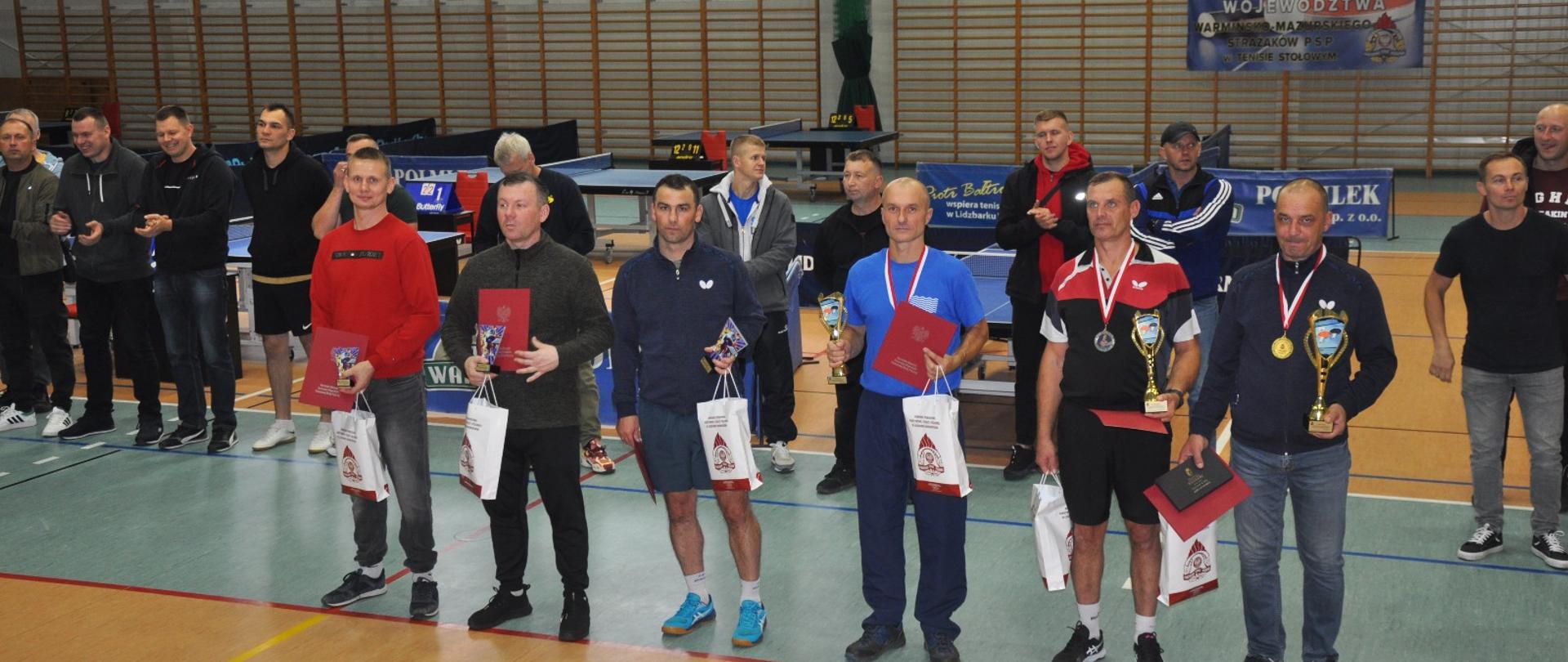 Zawodnicy na hali gimnastycznej z pucharami