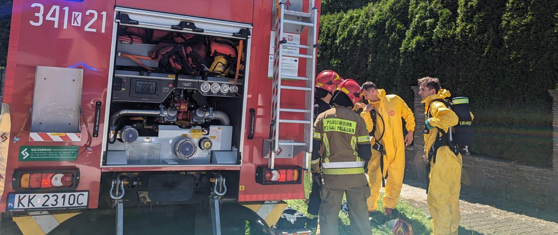 Strażacy obok samochodu pożarniczego