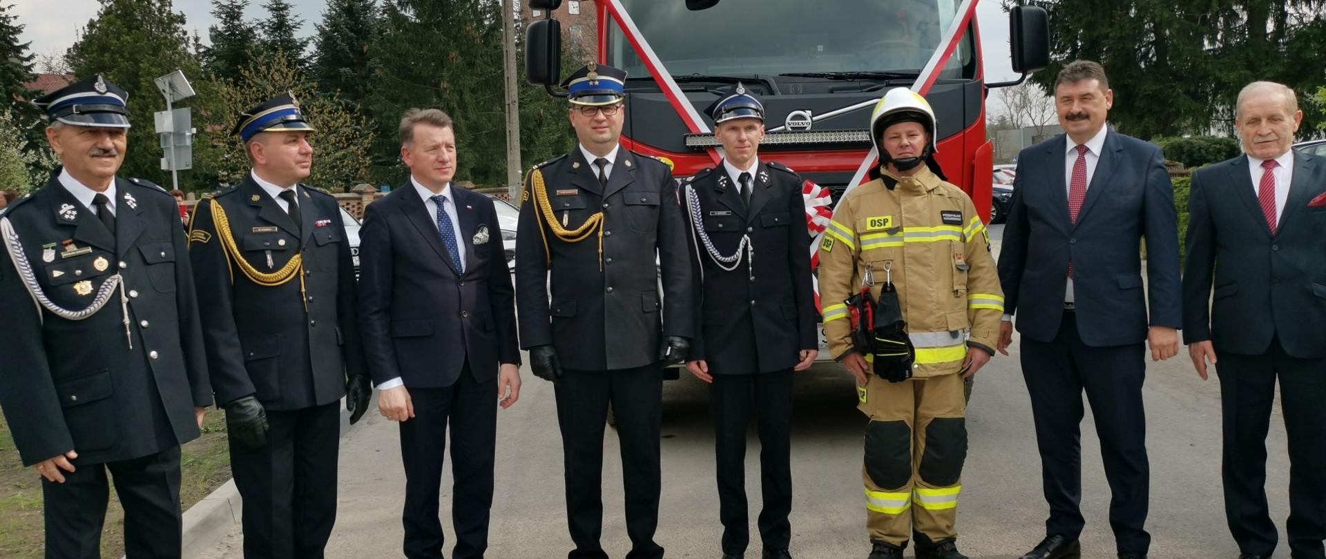 Zdjęcie przedstawia strażaków, druhów OSP i parlamentarzystów podczas przekazania nowego samochodu pożarniczego. 