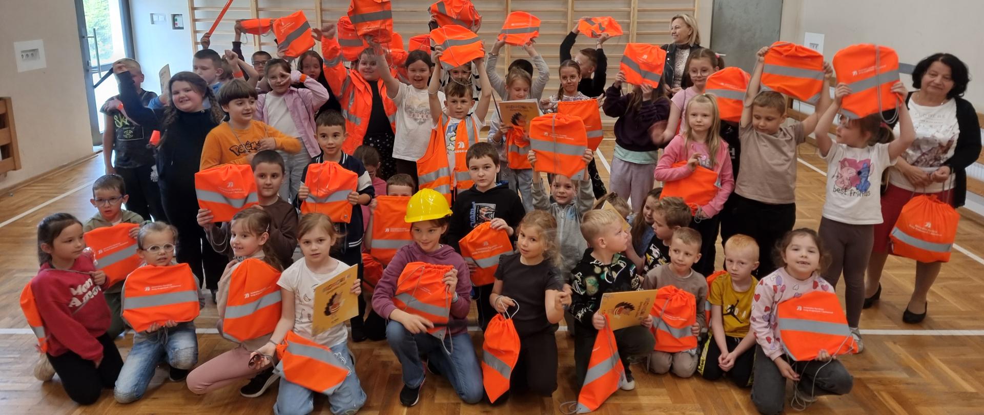 Lekcja edukacyjna - grupa dzieci z odblaskowymi pomarańczowymi woreczkami 
