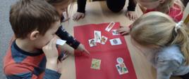 dzieci układają obrazki z niezdrowymi przekąskami na czerwonej planszy
