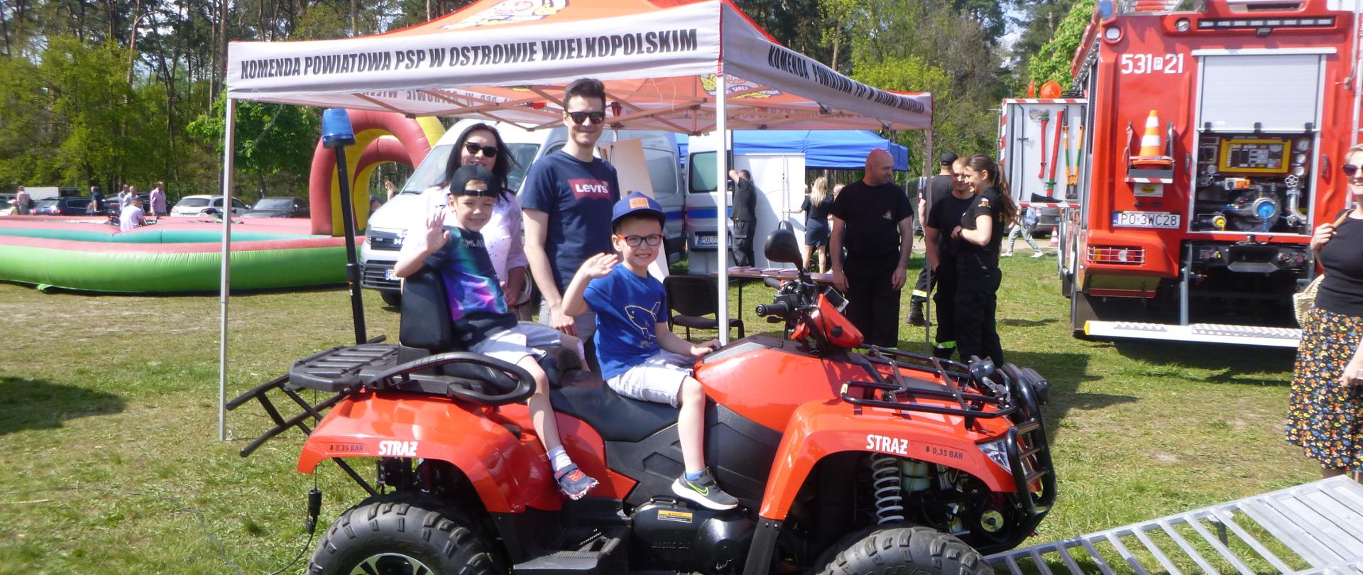 Stoisko KP PSP w Ostrowie Wielkopolskim prezentujące sprzęt straży pożarnej wykorzystywany do działań ratowniczo-gaśniczych. Wokoło sprzętu zgromadzona jest widownia.