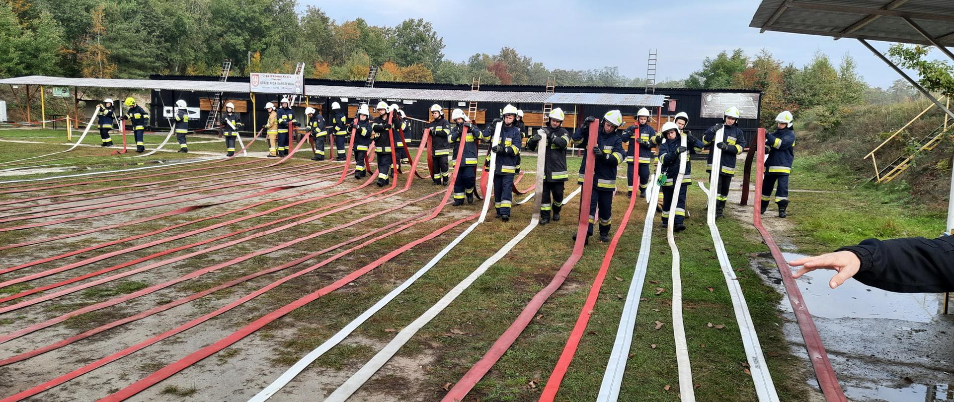 Uczestnicy egzaminu zwijają węże pożarnicze