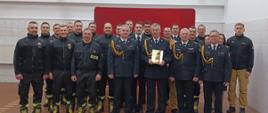 Zdjęcie grupowe przedstawia przechodzącego na zaopatrzenie emerytalne st. asp. Rafała Węgrzyn w towarzystwie Komendanta Powiatowego Państwowej Straży Pożarnej w Człuchowie st. bryg. Radosława Batruch, pracowników Komendy powiatowej PSP w Człuchowie.
