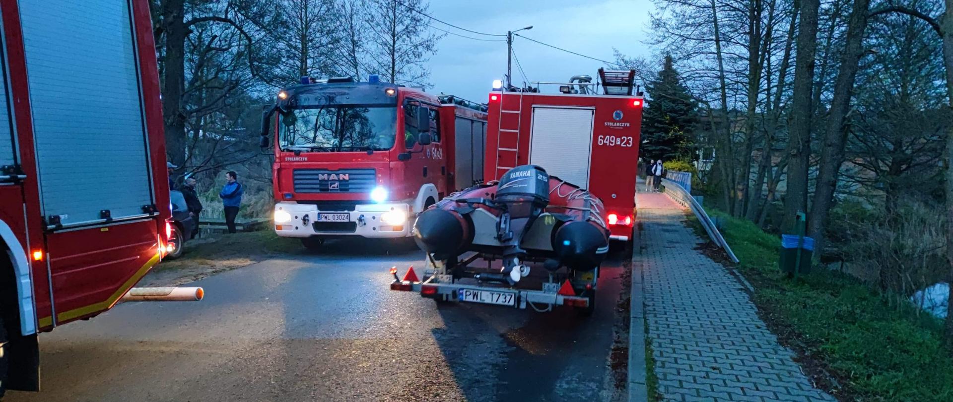 Zmierzch, droga, samochody strażackie, ponton, osoby postronne.