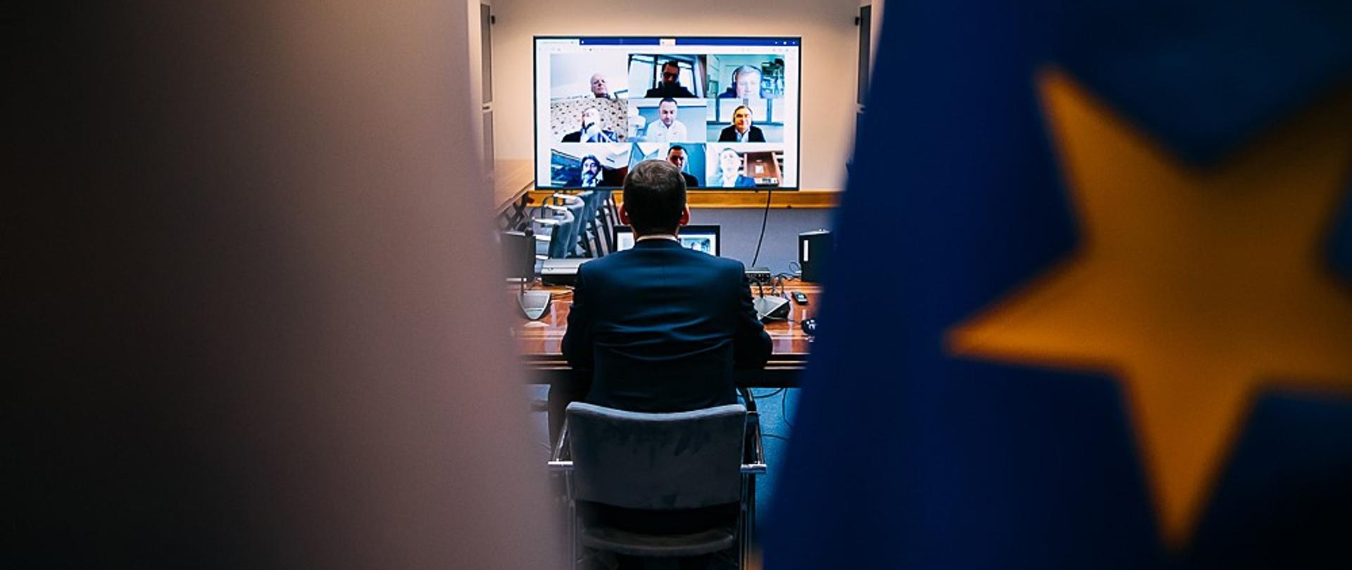Widok zza flag na trwającą wideokonferencję.