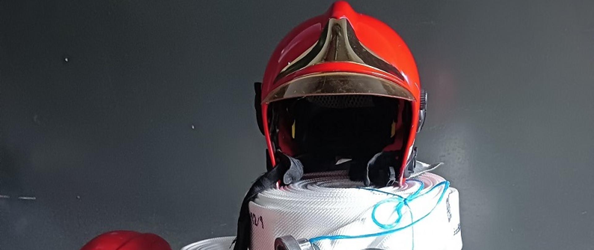 Na zdjęciu węże pożarnicze i hełmy na tle garażu KP PSP w Ostrowcu Św.