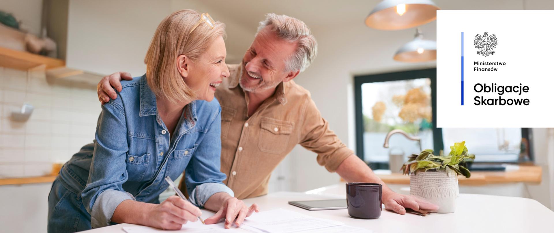 Uśmiechnięta para osób w kuchni. Ministerstwo Finansów, Obligacje Skarbowe.
