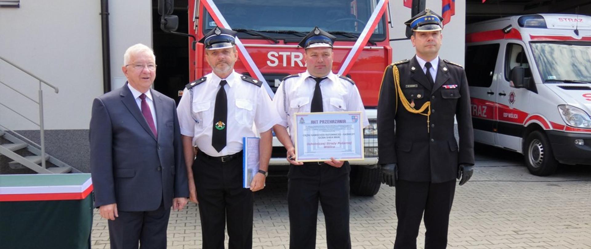 Zdjęcie przedstawia kolejno od lewej: Poseł na Sejm Krzysztof Lipiec, prezes OSP Wiślica dh Józef Siwy, kierowca OSP Wiślica dh Marcin Madej, st. bryg Krzysztof Ciosek Świętokrzyski Komendant Wojewódzki stojący na tle nowo pozyskanego pojazdu pożarniczego