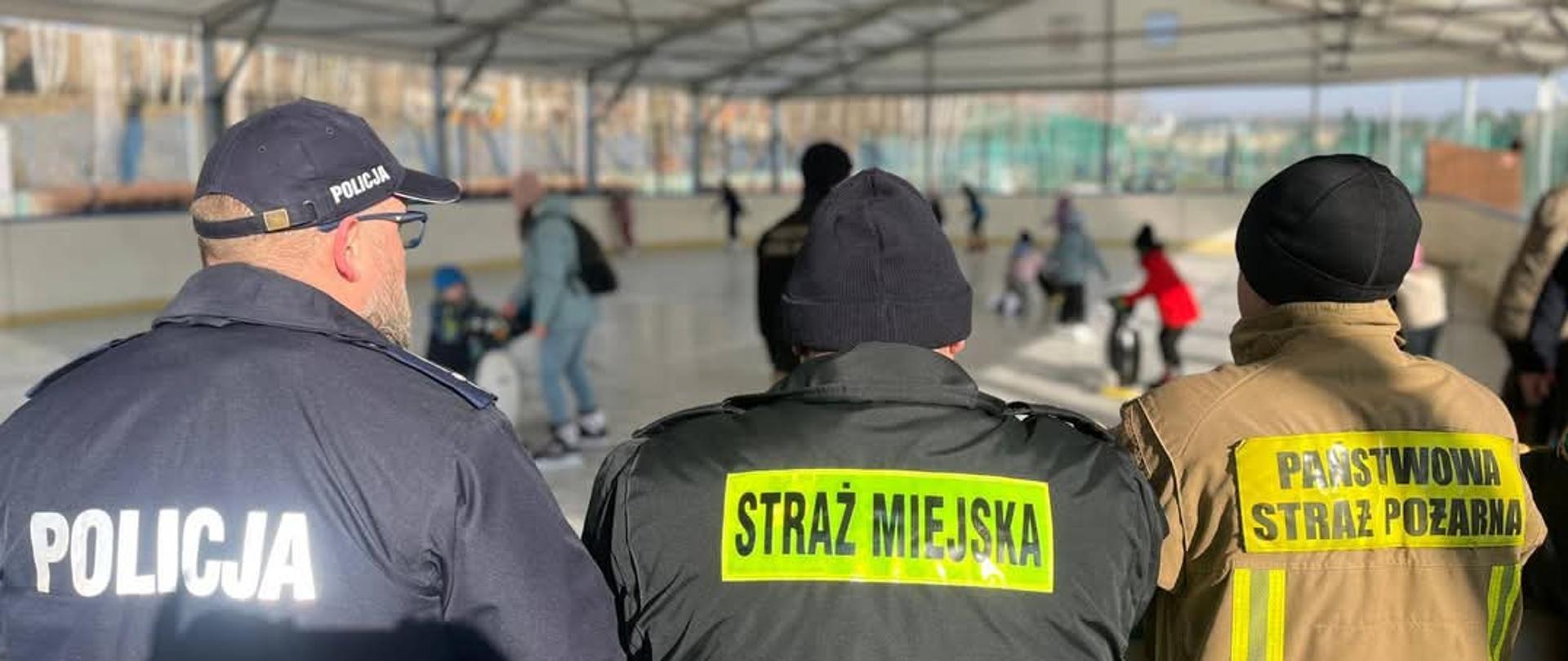 Policjant, Strażnik Miejski oraz Strażak zwracają uwagę na dzieci podczas zawodów.