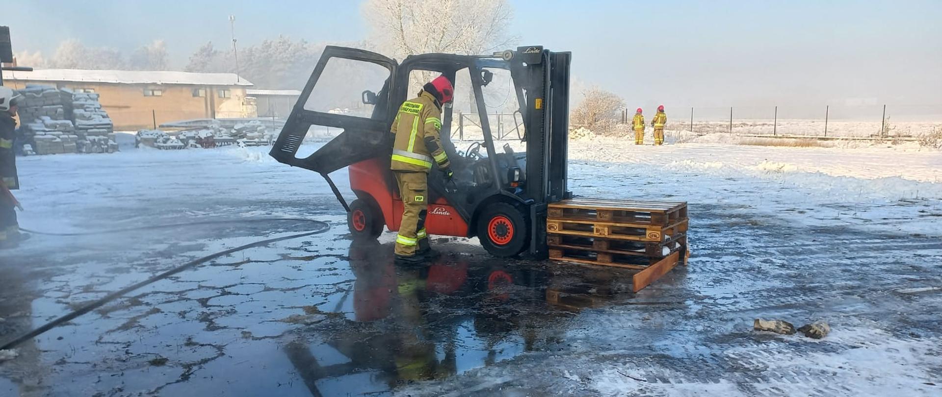 Nadpalony wózek widłowy, w tle strażacy