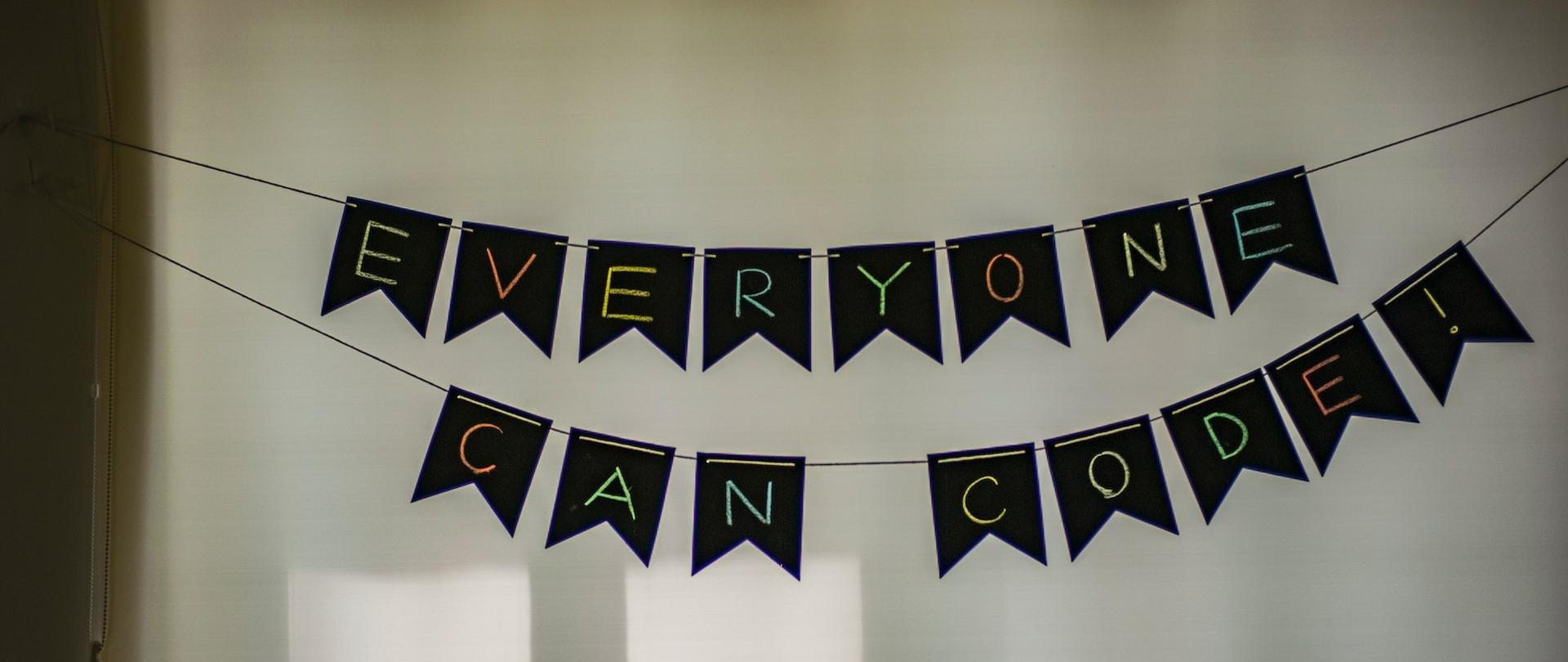 Napis: "Everyone can code!", ułożony z liter powieszonych na sznurkach.