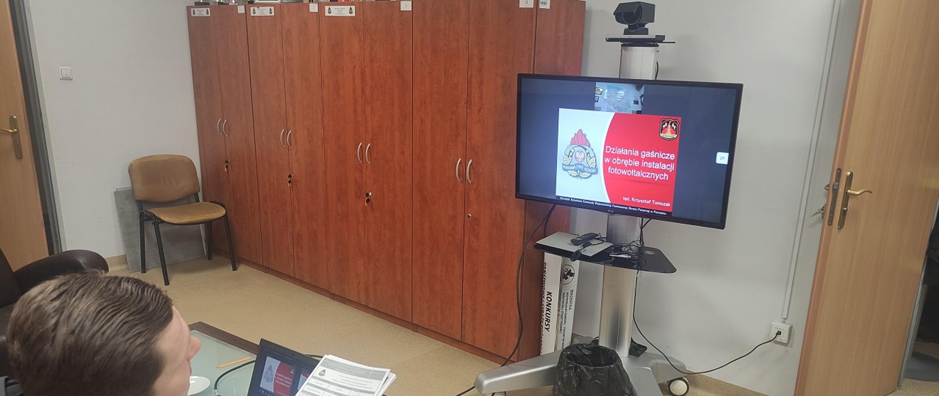 siedzący strażak z dokumentami w ręku przed telewizorem - szkolenie