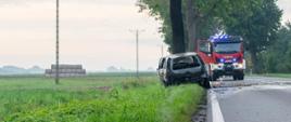 Na zdjęciu wrak samochodu spalonego kto®y uderzył w drzewo za nim na jezdni samochód ratowniczo - gaśniczy 