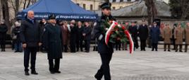 Funkcjonariusz niesie wieniec pod pomnik AK
