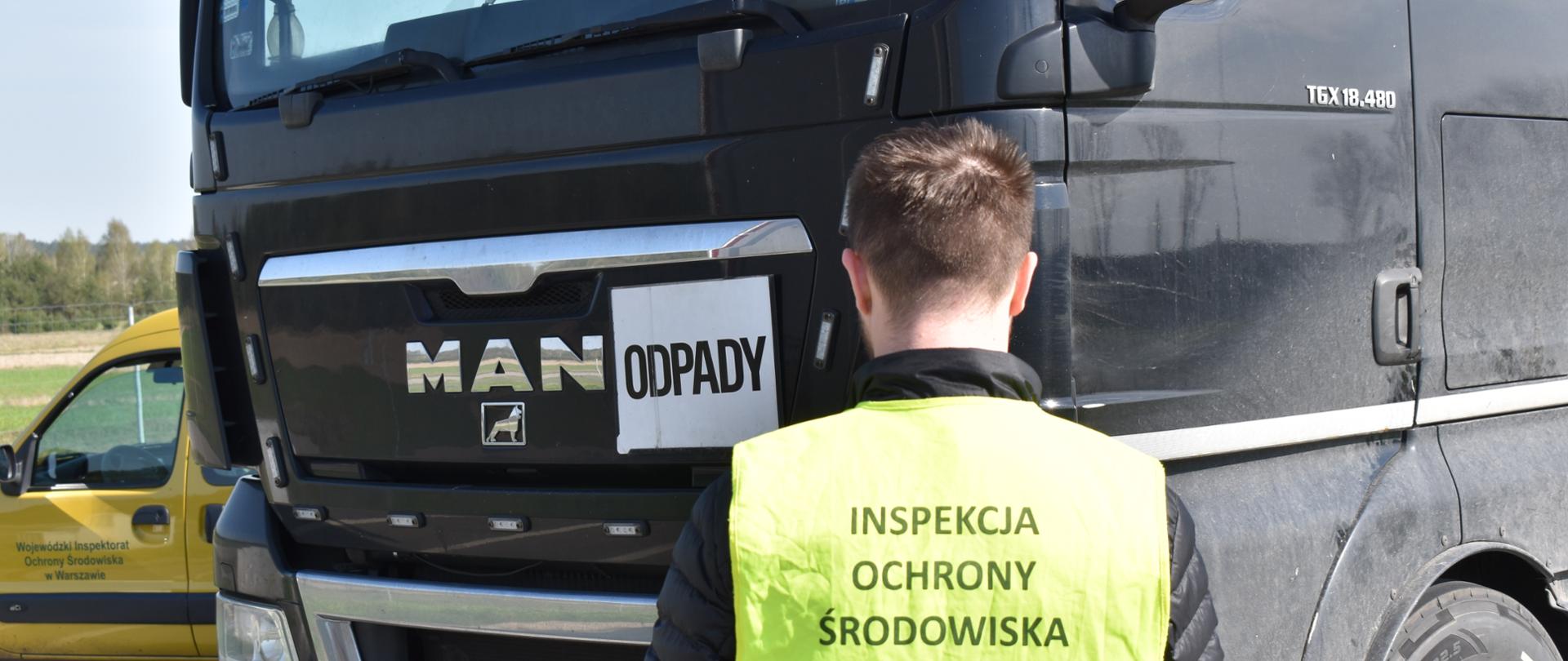 Inspektor Wojewódzkiego Inspektoratu Ochrony Środowiska w Warszawie prowadzi kontrolę samochodu ciężarowego.