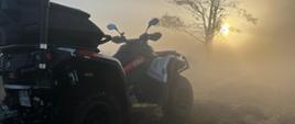 Na zdjęciu quad strażacki o wschodzie słońca w zadymionym terenie.