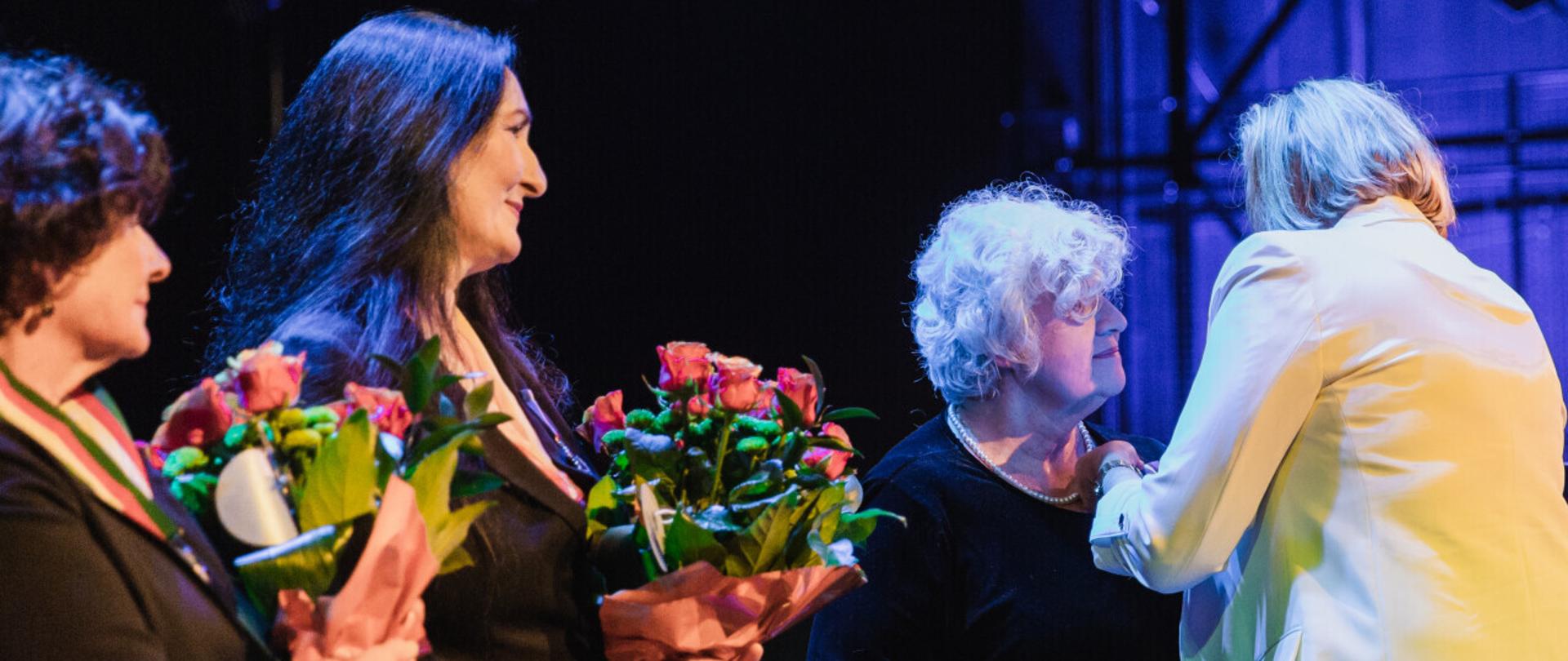 cztery kobiety stojące na scenie otrzymują medale "Zasłużony Kulturze Gloria Artis"