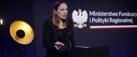Na zdjęciu minister funduszy i polityki regionalnej Katarzyna Pełczyńska-Nałęcz przy mównicy na scenie odpowiada na pytania dziennikarzy