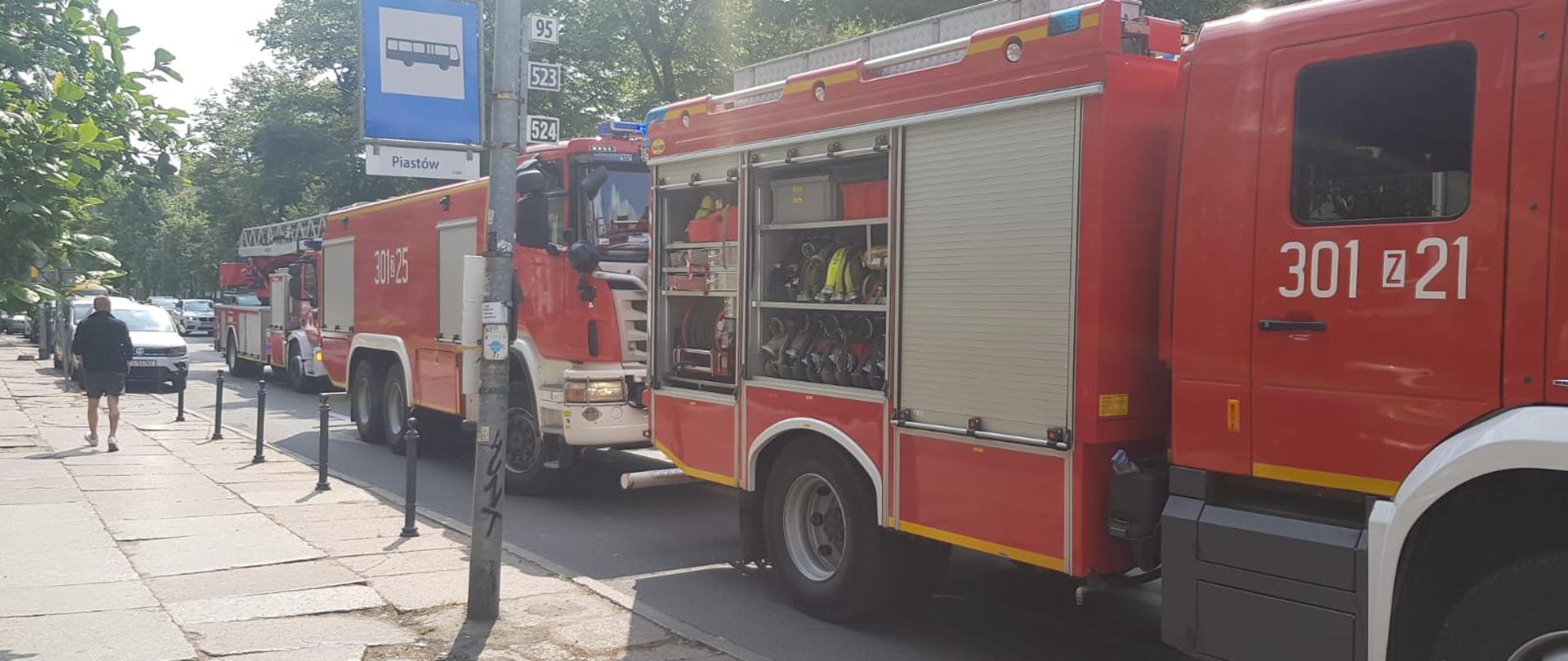 Trzy samochody ratowniczo gaśnicze Państwowej Straży Pożarnej w tym samochód z drabiną mechaniczną.