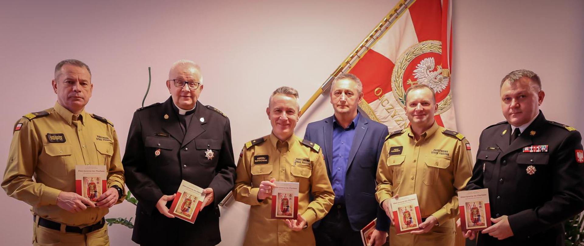 Na zdjęciu widać sześciu strażaków, którzy prezentują w dłoniach książkę "Etos Rycerzy św. Floriana"