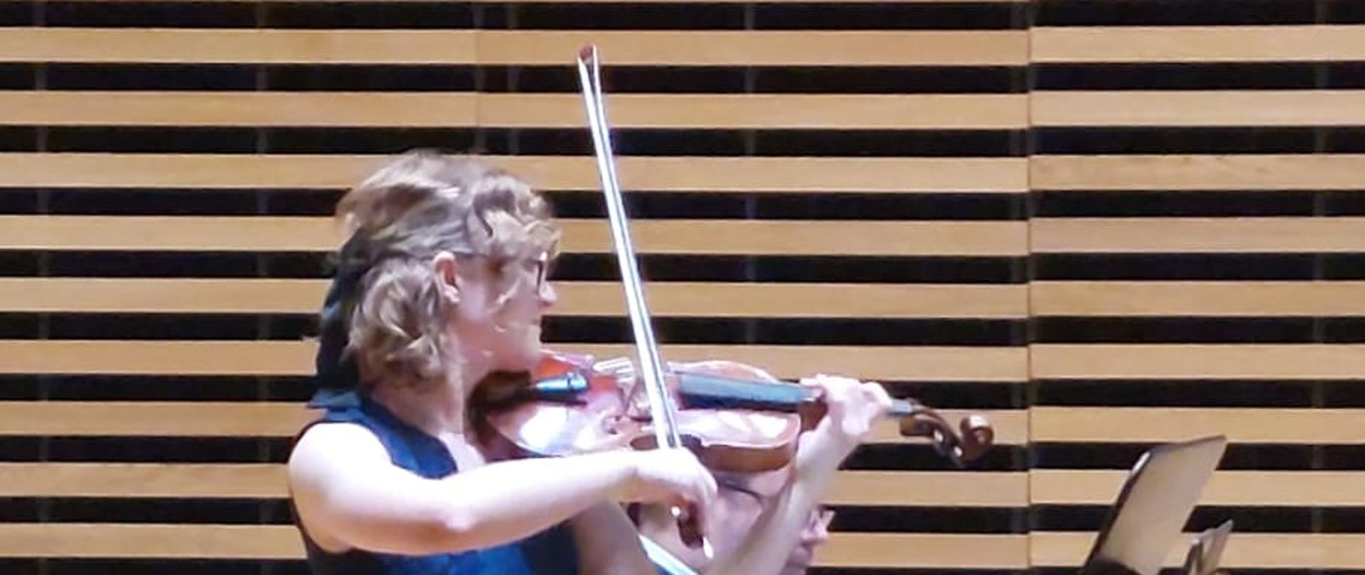 Dziewczyna gra na skrzypcach, mężczyzna akompaniuje na fortepianie.