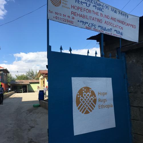  Zaprojektowany w ramach projektu logotyp Hope Rugs Ethiopia na bramie siedziby HBRHA. Autor: Maciej Chrzanowski, 2020.12.14, Addis Abeba,