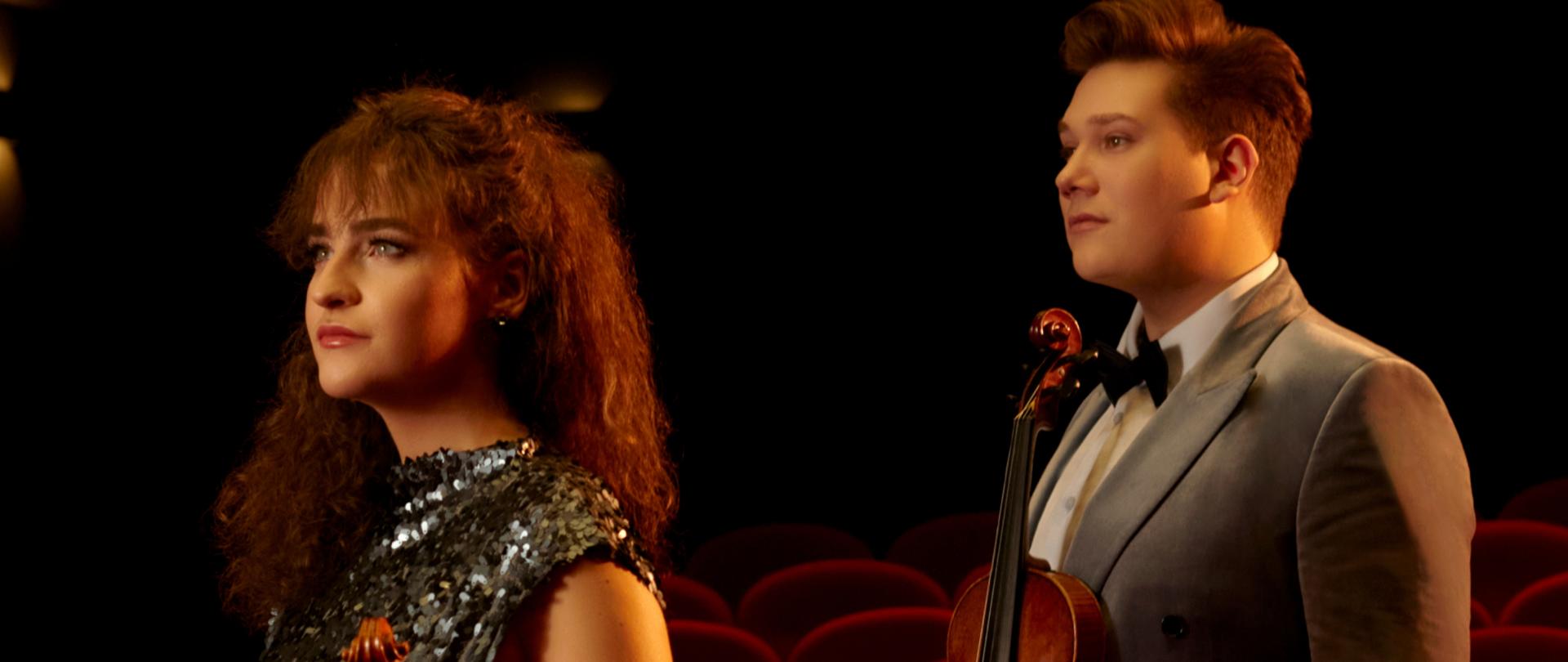 informacje o koncercie duetu skrzypcowego, dwie osoby trzymające skrzypce na tle kilku rzędów krzeseł na sali koncertowej, górna część plakatu na czarnym tle