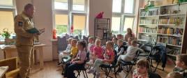 Zastępca Komendanta Powiatowego czyta dzieciom