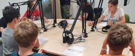 Dzieci siedzą w studio radiowym przed mikrofonami