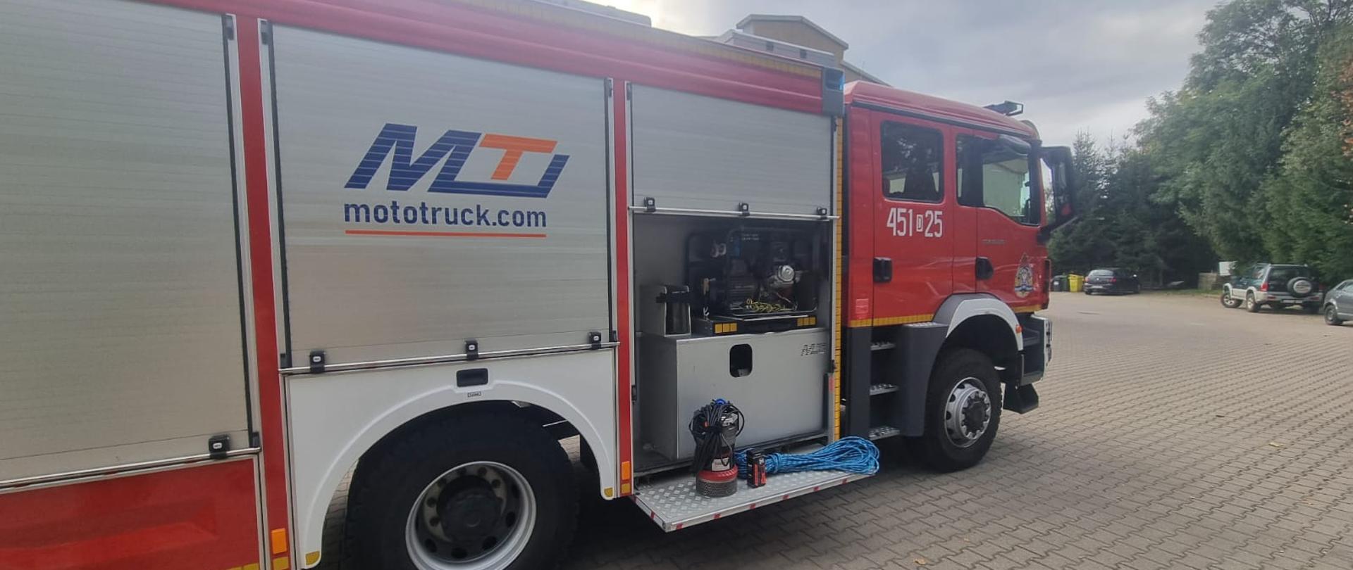 Samochód ratowniczo gaśniczy z otwartą jedną skrytką oraz podestem, na którym umieszczono pompę, linę oraz latarkę.