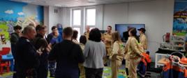 Młodzież w sali edukacyjnej słucha przemówienia strażaków.