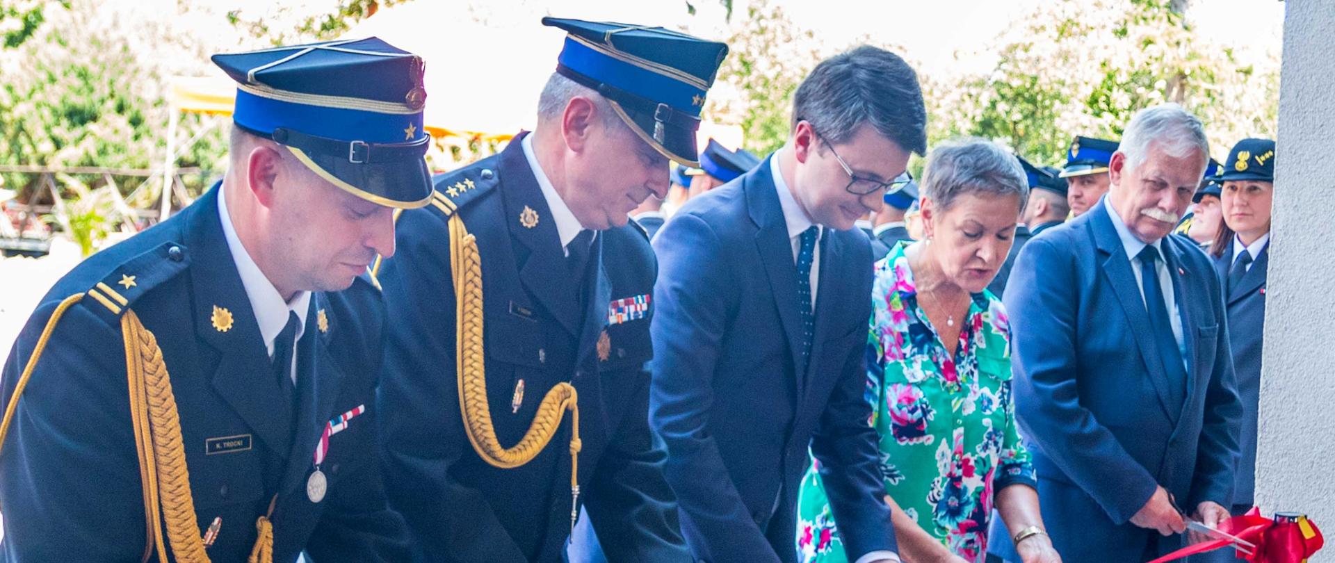 Na zdjęciu widać uroczyście przecinających wstęgę od lewej Komendant Miejski PSP w Słupsku, Pomorski Komendant Wojewódzki PSP, Sekretarz Stanu w KPRM, rzecznik prasowy Rządu, poseł na na Sejm RP, Prezydent Miasta Słupska oraz wicewojewodę pomorskiego.
