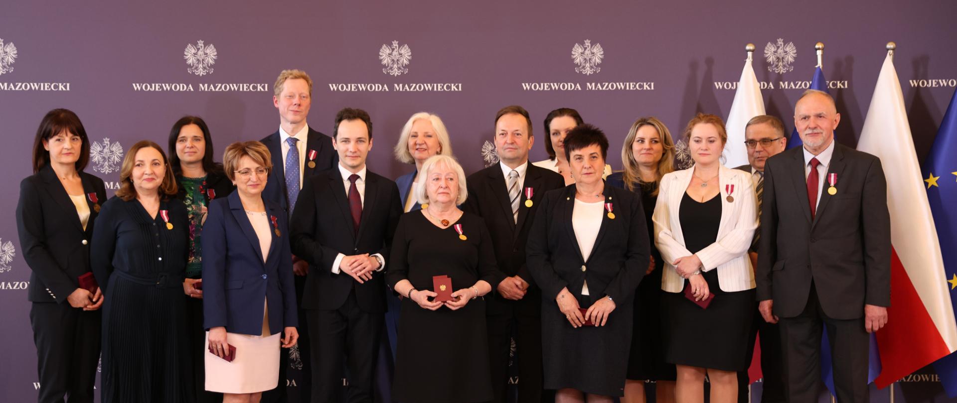 Na zdjęciu grupa ludzi odznaczonych medalami. Z boku stoi flaga Polski i Unii Europejskiej 