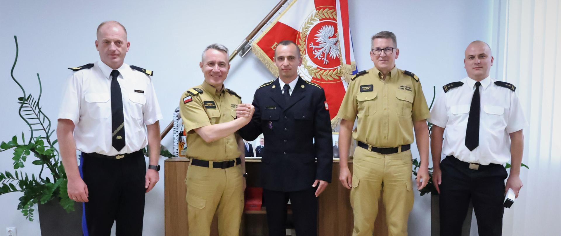 Zdjęcie pamiątkowe uczestników spotkania na tle sztandaru