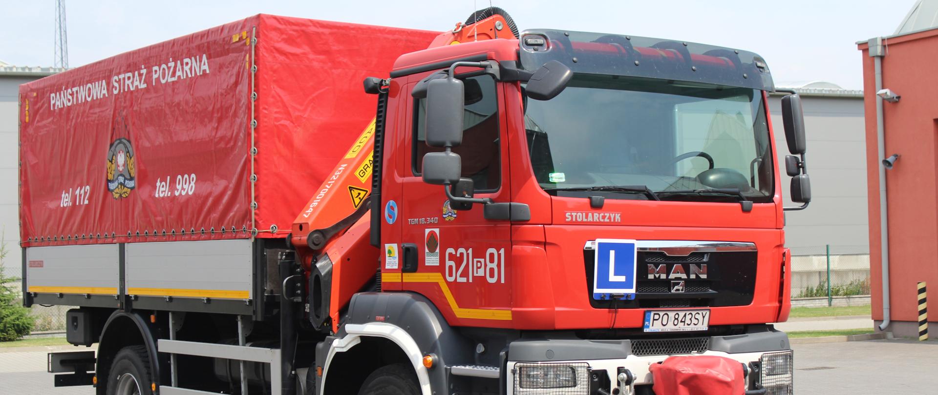 samochód strażacki, z przodu ma literę L na niebieskim tle