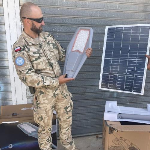 Żołnierz ogląda trzymany w rękach fragment lampy solarnej