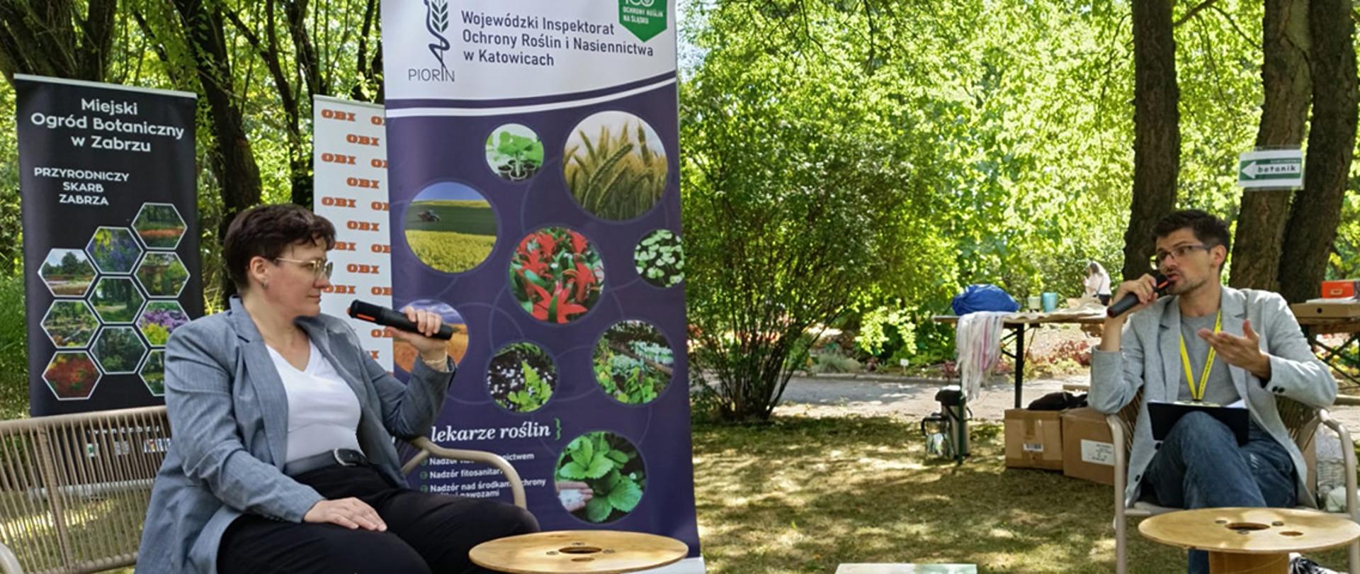 Wywiad z inspektorką WIORiN. Na zdjęciu widoczne są 2 osoby, trzymające mikrofony i rozmawiające. W tle ogórd botaniczny